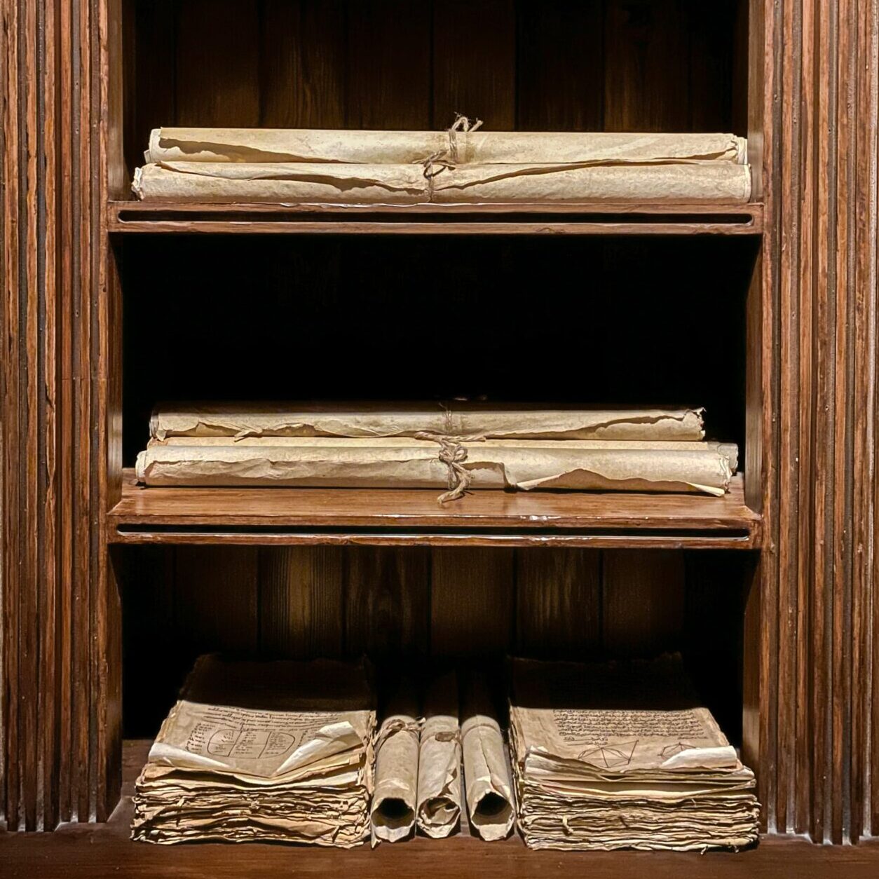a collection of old scrolls on wooden shelves